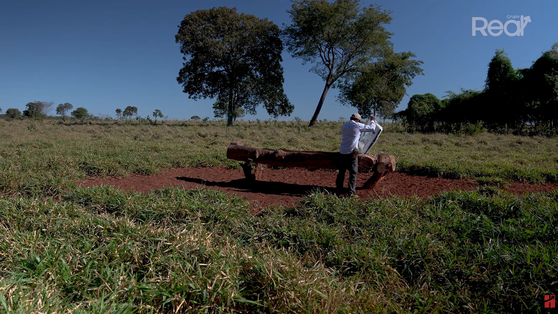 Homem trabalhando em campo aberto com vegetação.